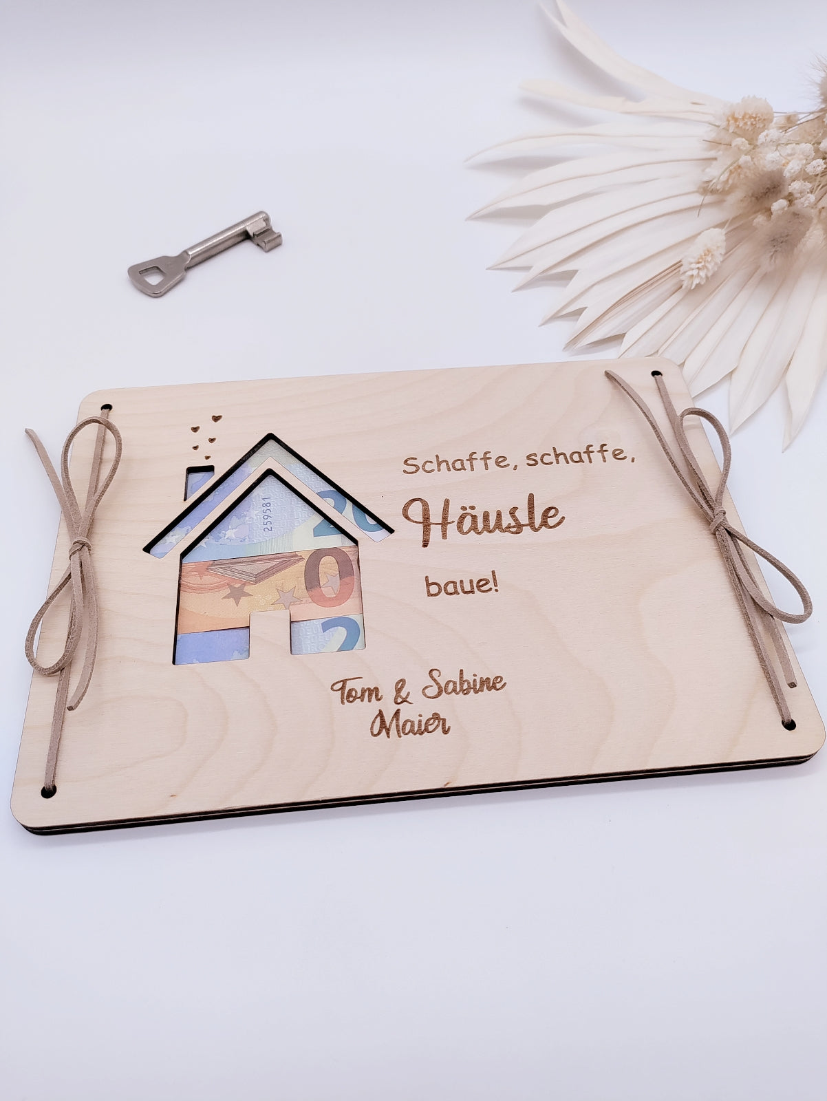 Geldgeschenk zur Hauseinweihung – Holzplatte mit Haus-Motiv, durch das ein Geldschein sichtbar ist. Perfekt als Geschenk zum Richtfest oder Bauanlass.