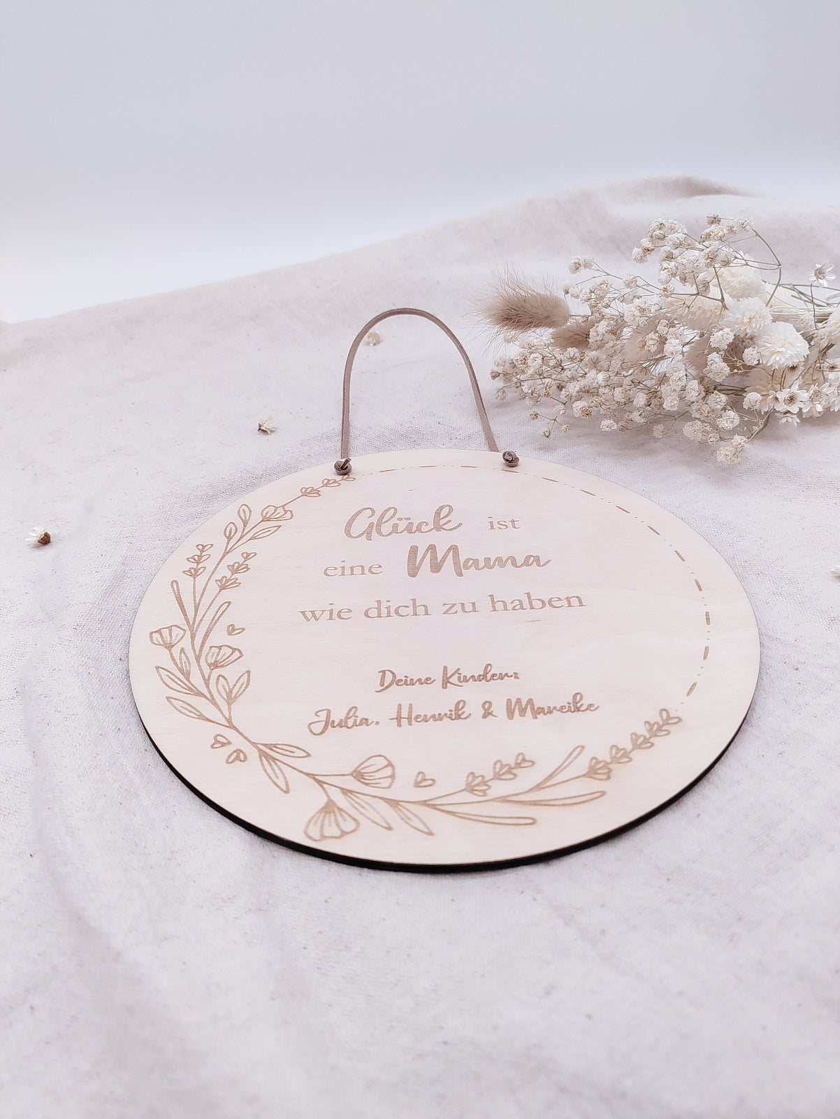 Personalisiertes Muttertags-Schild aus Birkensperrholz mit Gravur „Glück ist eine Mama wie dich zu haben“, verziert mit Blumenranke und veganer Lederschnur zum Aufhängen. Ein einzigartiges Geschenk zum Muttertag.