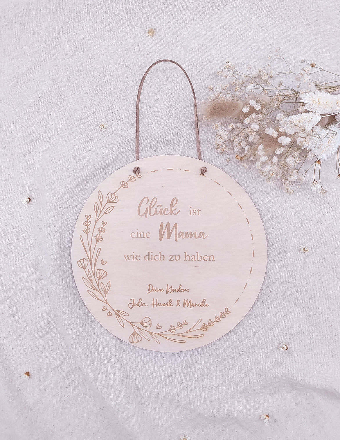 Personalisiertes Muttertags-Schild aus Birkensperrholz mit Gravur „Glück ist eine Mama wie dich zu haben“, verziert mit Blumenranke und veganer Lederschnur zum Aufhängen. Ein einzigartiges Geschenk zum Muttertag.
