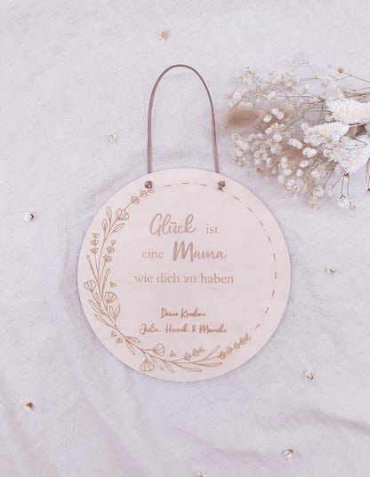 Personalisiertes Muttertags-Schild aus Birkensperrholz mit Gravur „Glück ist eine Mama wie dich zu haben“, verziert mit Blumenranke und veganer Lederschnur zum Aufhängen. Ein einzigartiges Geschenk zum Muttertag.