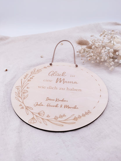 Personalisiertes Muttertags-Schild aus Birkensperrholz mit Gravur „Glück ist eine Mama wie dich zu haben“, verziert mit Blumenranke und veganer Lederschnur zum Aufhängen. Ein einzigartiges Geschenk zum Muttertag.